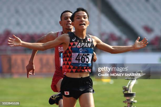 Japan's Hiroto Inoue gestures as he crosses the finish line ahead of Bahrain's Elhassan Elabbassi to win the men's marathon athletics event during...