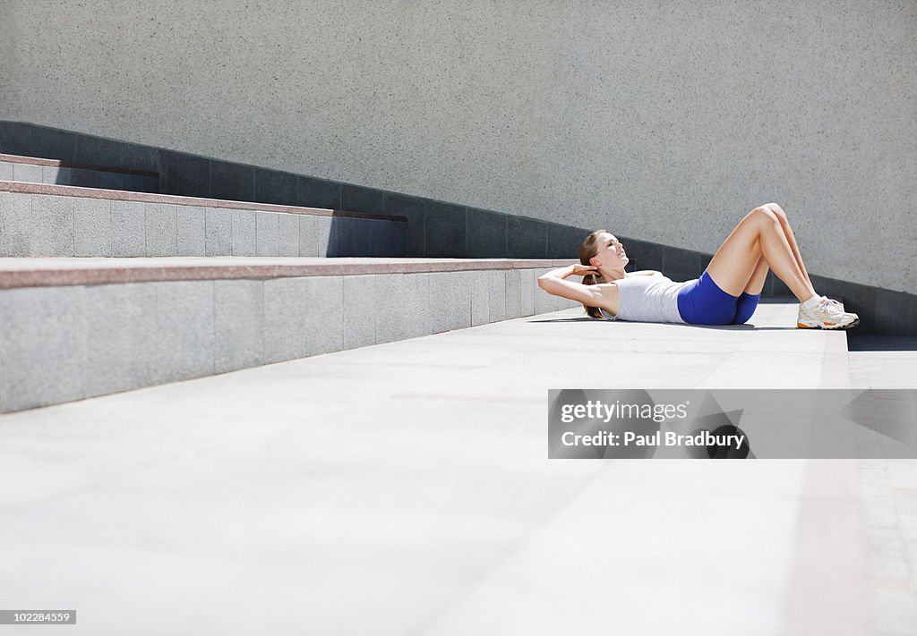 Woman doing sit-ups on urban stairs