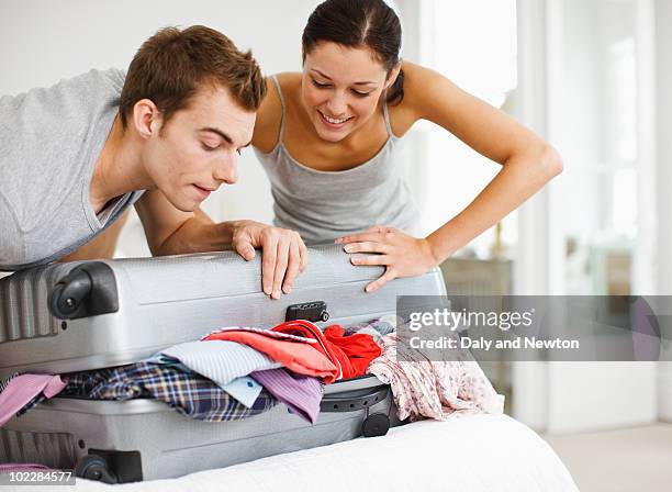 couple trying to close full suitcase - suitcase close foto e immagini stock