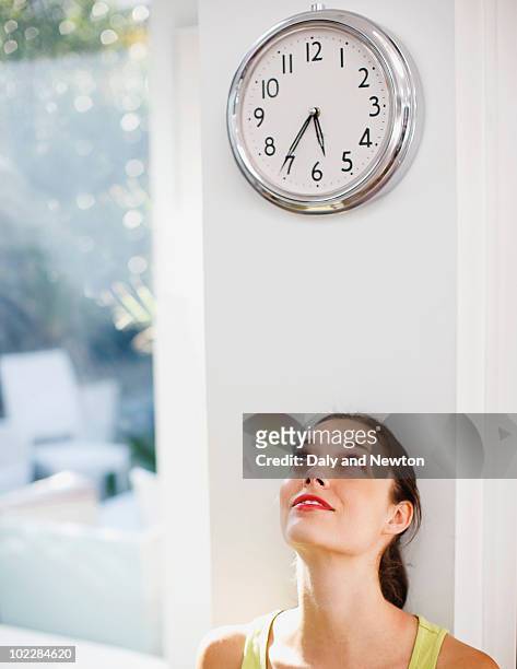 woman looking at clock - frau uhr stock-fotos und bilder