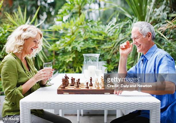 couple playing chess outdoors - senior playing chess stock pictures, royalty-free photos & images