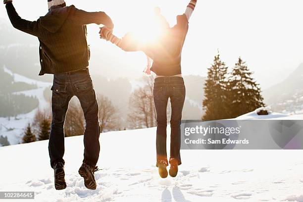 paar springen im freien im schnee - moutain sunset snow stock-fotos und bilder