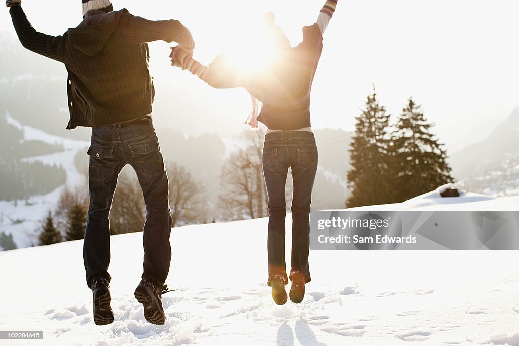 Couple jumping outdoors in snow