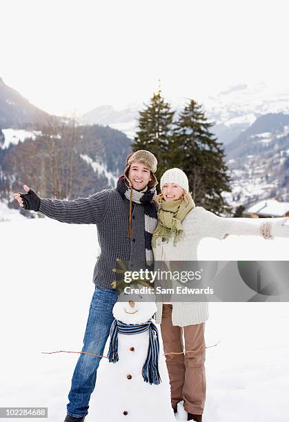 paar stehend mit schneemann - frau schneemann stock-fotos und bilder