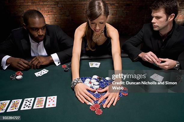 woman gathering poker chips in casino - poker stock pictures, royalty-free photos & images