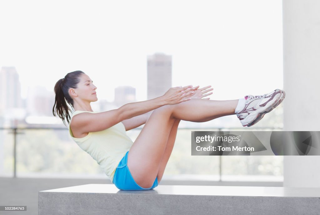 Woman doing sit-ups in urban setting