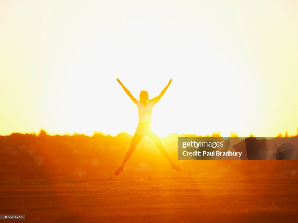 Femme sauter dans le parc au coucher du soleil