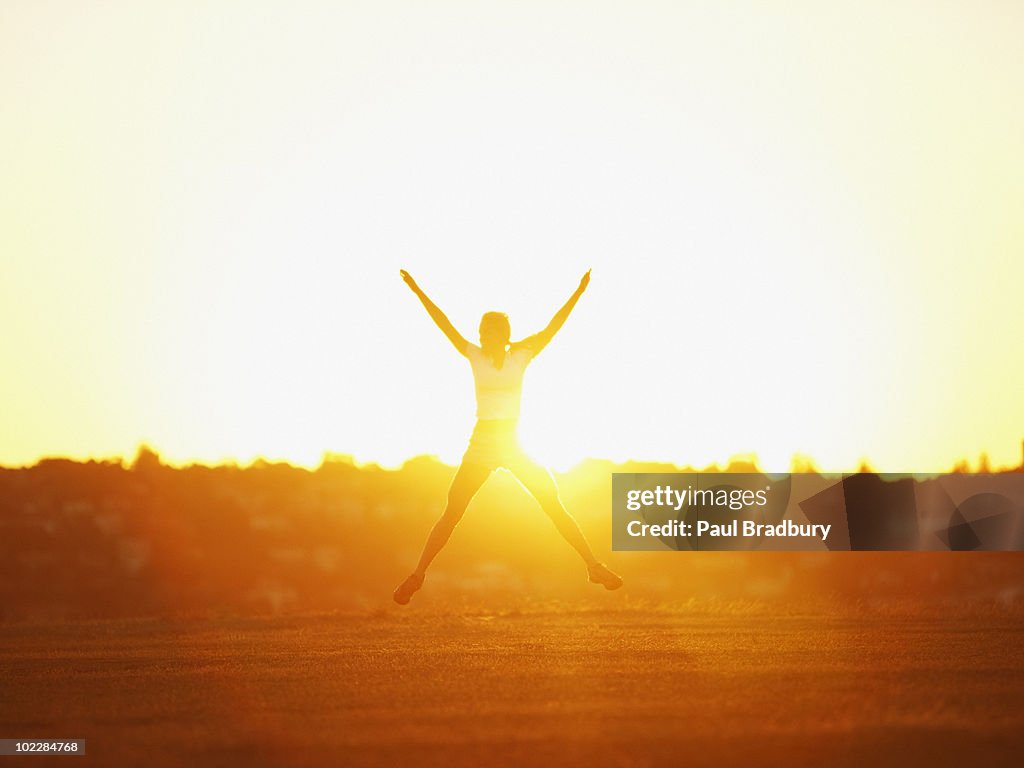 Woman jumping in park at sunset