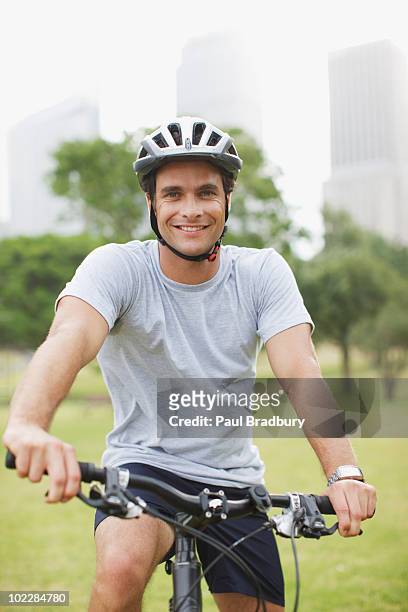 man riding bicycle in urban park - man wearing helmet stock pictures, royalty-free photos & images
