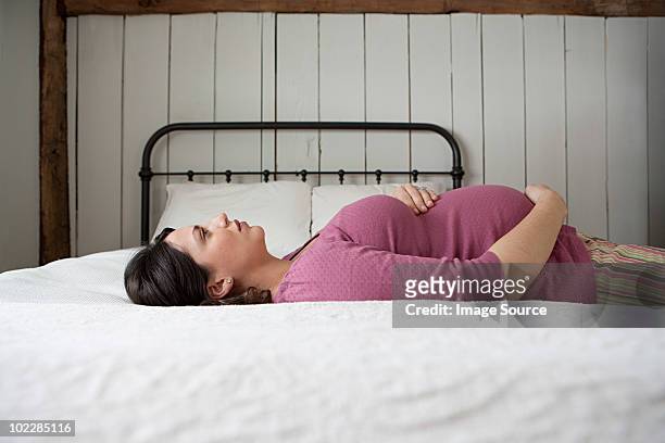 pregnant woman lying on bed - human abdomen foto e immagini stock