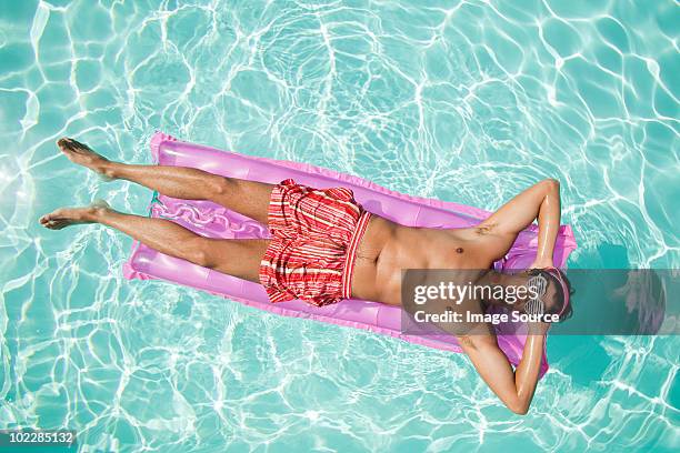 man on inflatable mattress in pool - pool raft imagens e fotografias de stock