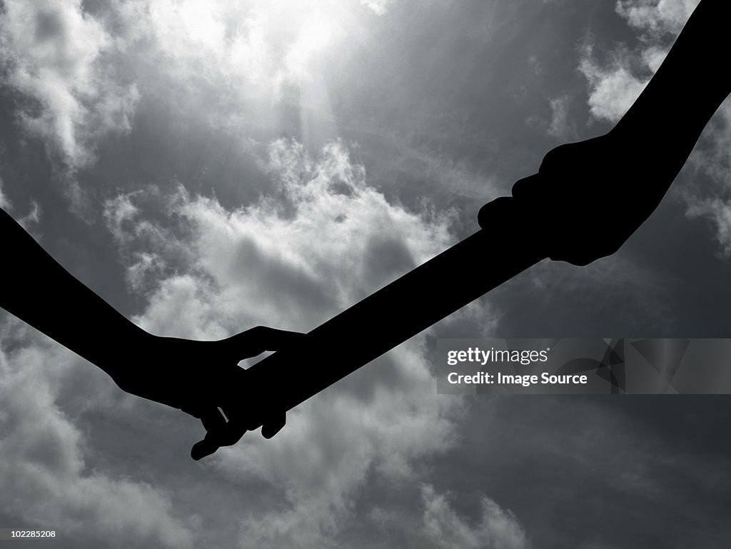 Silhouette of people passing relay baton