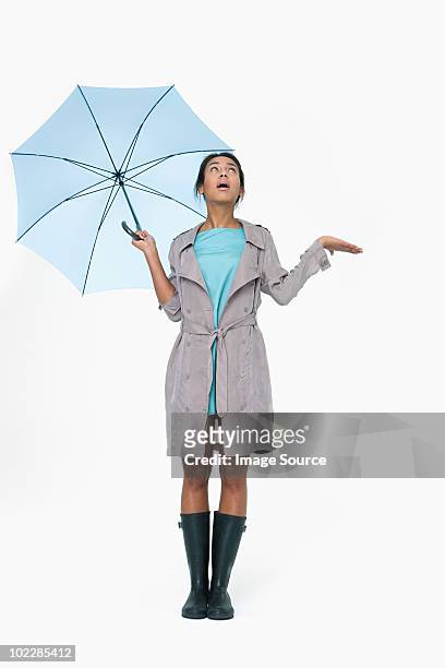 young woman holding umbrella and looking up - holding umbrella stock pictures, royalty-free photos & images