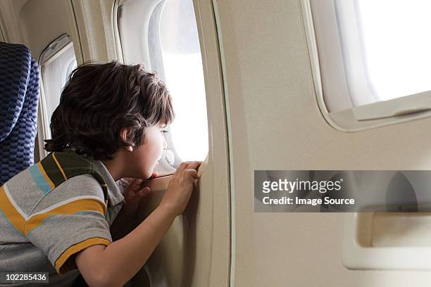 boy looking through window on an airplane - young traveller stock pictures, royalty-free photos & images