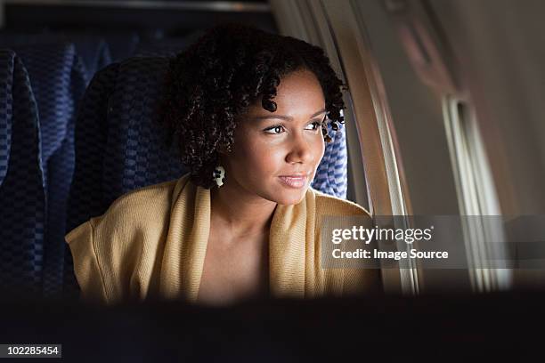 weibliche flugzeug passagier schaut aus dem fenster - flugzeugsitz stock-fotos und bilder