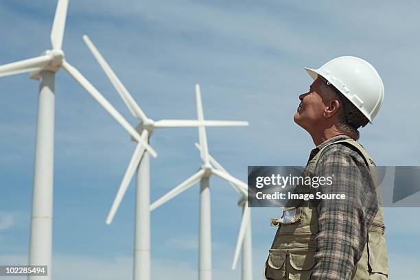 man in hard hat looking at wind turbines - wind turbine california stock pictures, royalty-free photos & images