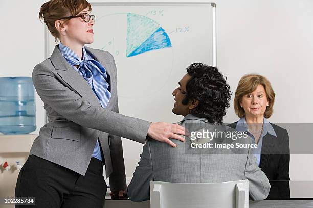 businesswoman sticking adhesive note to man's back - harassment man woman office stock-fotos und bilder