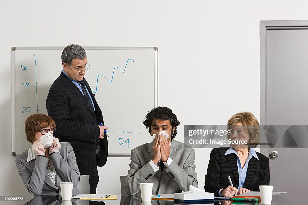 Businessman blowing nose in office