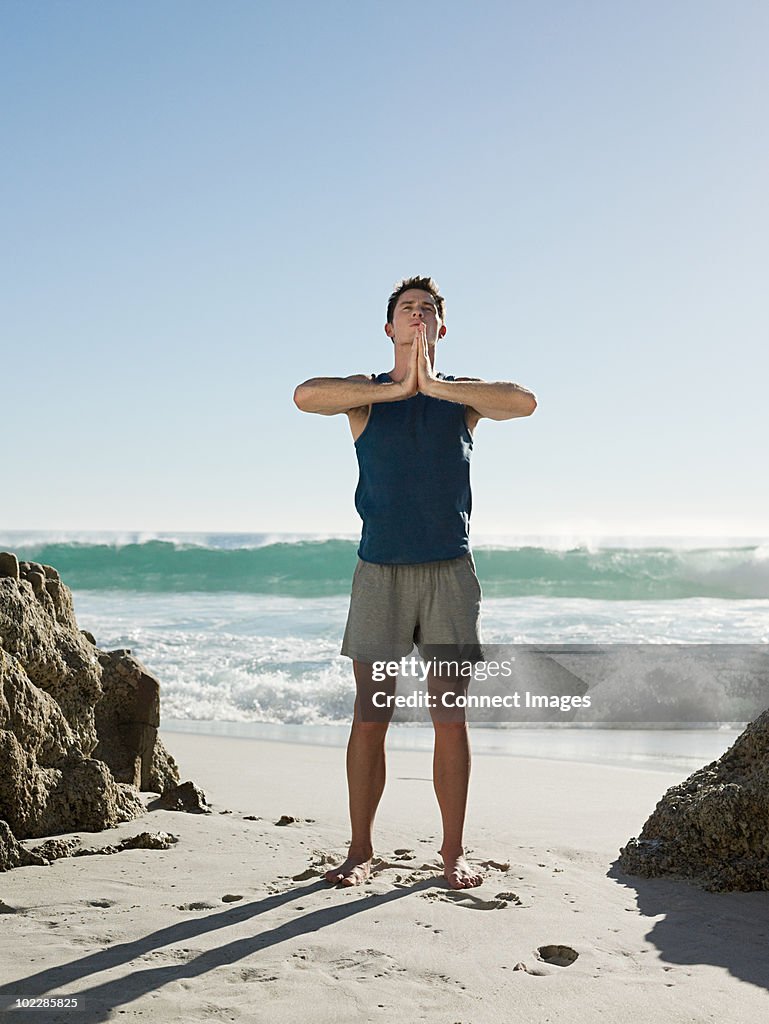 Junger Mann tun yoga am Strand