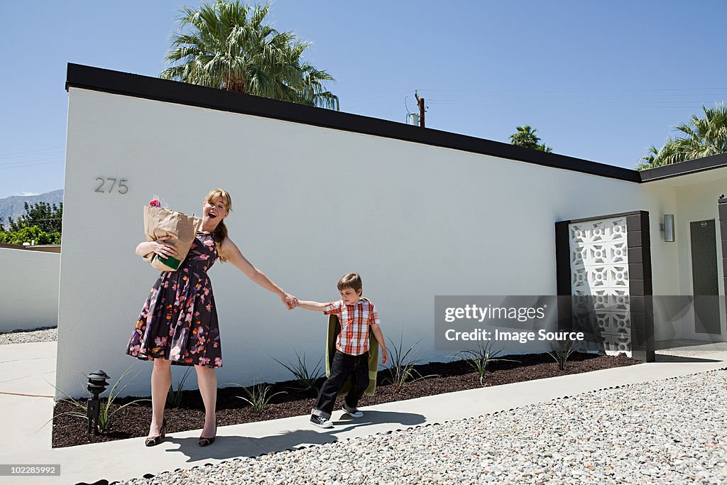 Mother holding shopping bag and pulling son's arm