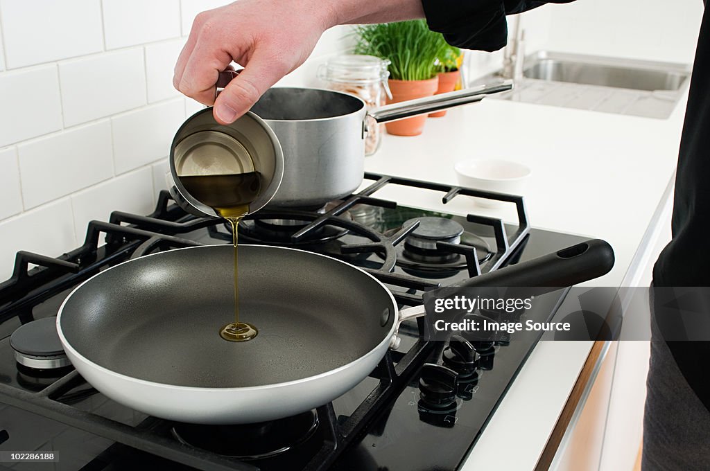 男性の食用油を注ぐ frying pan