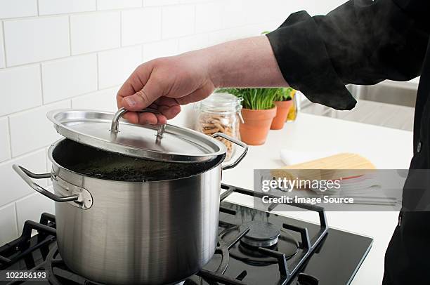 man lifting lid on saucepan - deksel stockfoto's en -beelden