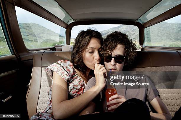 young couple inside car drinking soda - drinking soda in car stock pictures, royalty-free photos & images