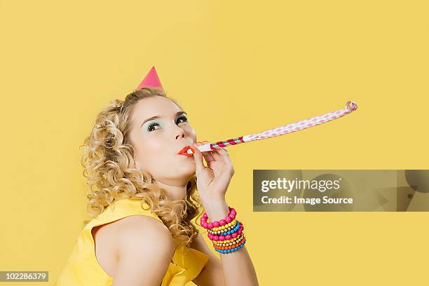 young woman wearing party hat with party blower - matasuegras fotografías e imágenes de stock