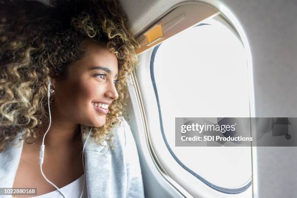 woman looking through window on airplane - banco de avião imagens e fotografias de stock