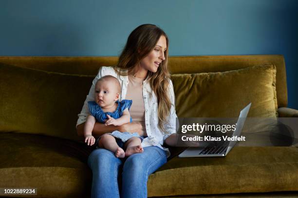 mother sitting with new born baby and laptop - young family in kitchen stock pictures, royalty-free photos & images