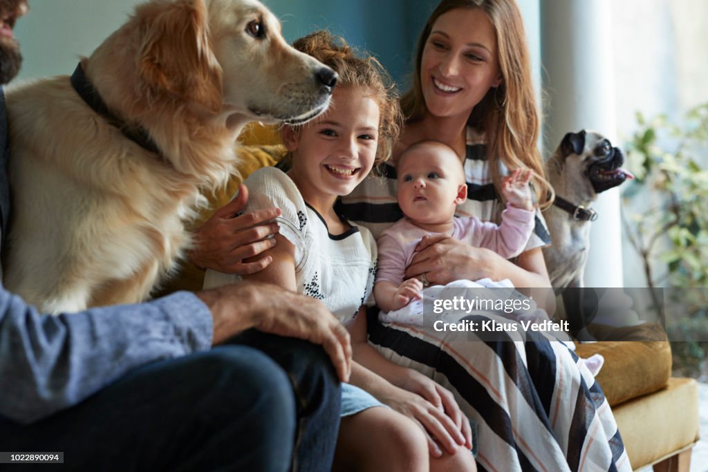 Family sitting together in sofa with their dogs