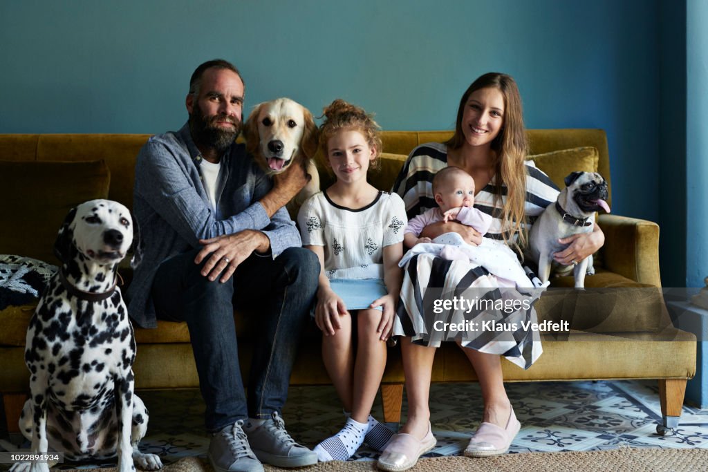 Family sitting together in sofa with their dogs