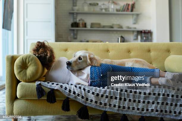 girl sleeping on couch with her golden retriever dog - people on sofa stock-fotos und bilder