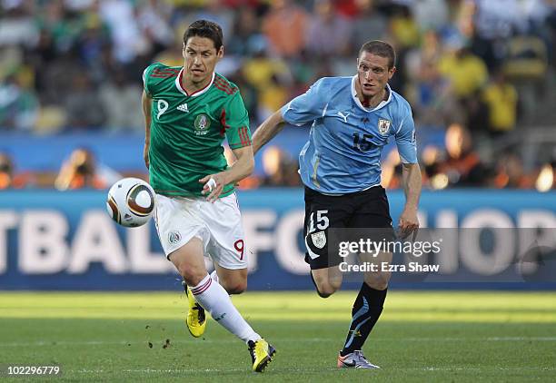 Guillermo Franco of Mexico and Diego Perez of Uruguay battle for the ball as Perez has blood pouring from a head injury during the 2010 FIFA World...