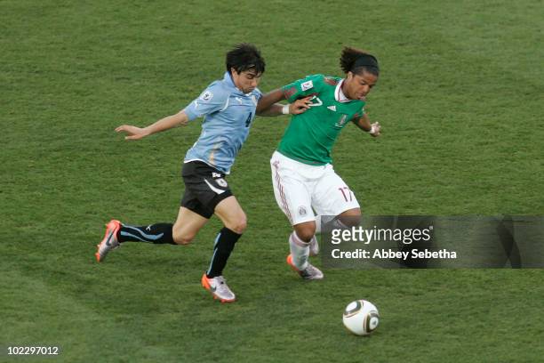 Jorge Fucile of Uruguay and Giovani Dos Santos of Mexico battle for the ball during the 2010 FIFA World Cup South Africa Group A match between Mexico...