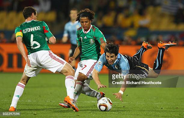 Jorge Fucile of Uruguay is tackled by Gerardo Torrado of Mexico during the 2010 FIFA World Cup South Africa Group A match between Mexico and Uruguay...