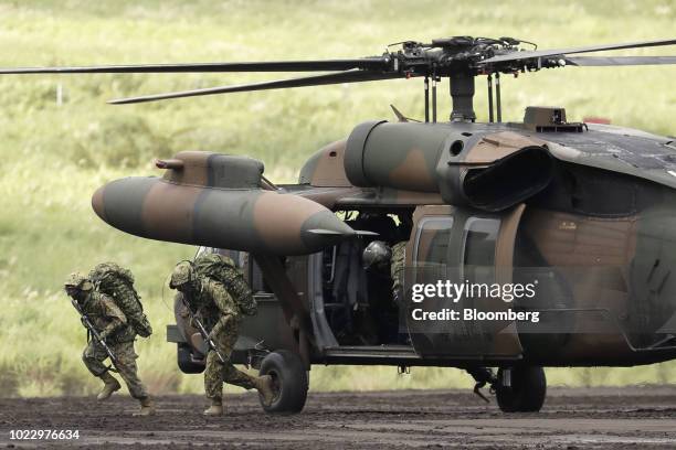 Members of the Japan Ground Self-Defense Force disembark from a UH-60 Black Hawk utility helicopter during a live fire exercise at the foot of Mount...