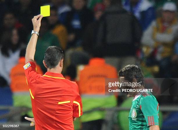 Hungarian referee Viktor Kassai gives Mexico's midfielder Israel Castro a yellow card fights for the ball with during their Group A first round 2010...