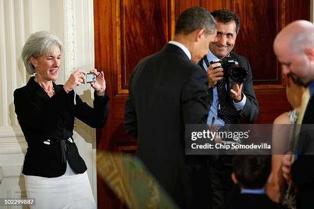 Health and Human Services Secretary Kathleen Sebelius and White House photographer Pete Souza make images of U.S. President Barack Obama signing...