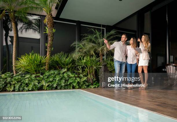 couple and real estate agent looking at a luxury property all looking very happy - luxury property stock pictures, royalty-free photos & images