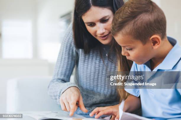 boy getting tutored with school assignment - professor particular imagens e fotografias de stock