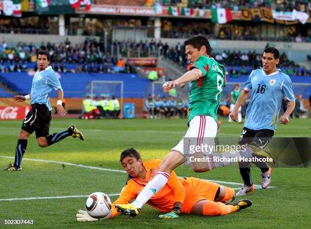 Guillermo Franco of Mexico attempts to round goalkeeper Fernando Muslera of Uruguay during the 2010 FIFA World Cup South Africa Group A match between...