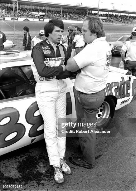 Driver Darrell Waltrip talks to member of his crew as they stand beside Waltrip's racecar prior to the start of the 1980 Daytona 500 stock car race...