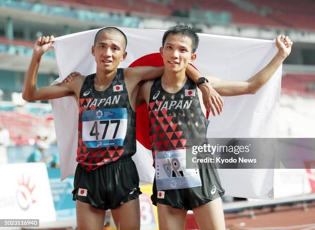 Men's marathon champion Hiroto Inoue and fourth-place Hayato Sonoda, both from Japan, pose with their country's flag after competing at the Asian...