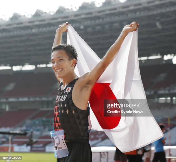 Japan's Hiroto Inoue raises his country's flag after winning Japan's first gold in 32 years in the men's marathon at the Asian Games in Jakarta on...
