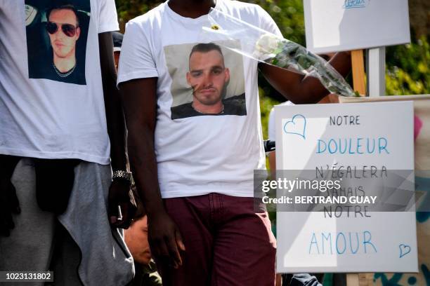 Man holds a placard reading "our grief will never equal our love" during a march on August 25, 2018 in Vigneux-sur-Seine, southern suburbs of Paris,...