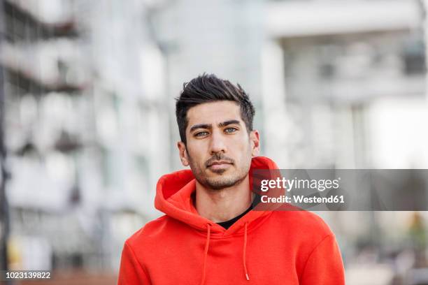 portrait of fashionable young man wearing red hooded jacket - man and his hoodie stockfoto's en -beelden