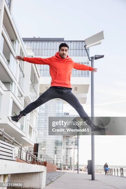 germany, cologne, portrait of young man jumping in the air - menswear bildbanksfoton och bilder
