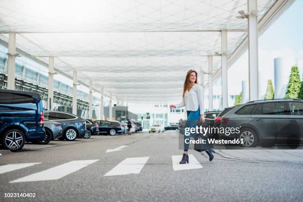 young woman with bag crossing street at zebra crossing - parking foto e immagini stock