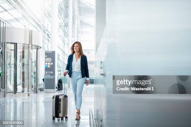 young businesswoman walking with luggage at the airport - flughafen stock-fotos und bilder